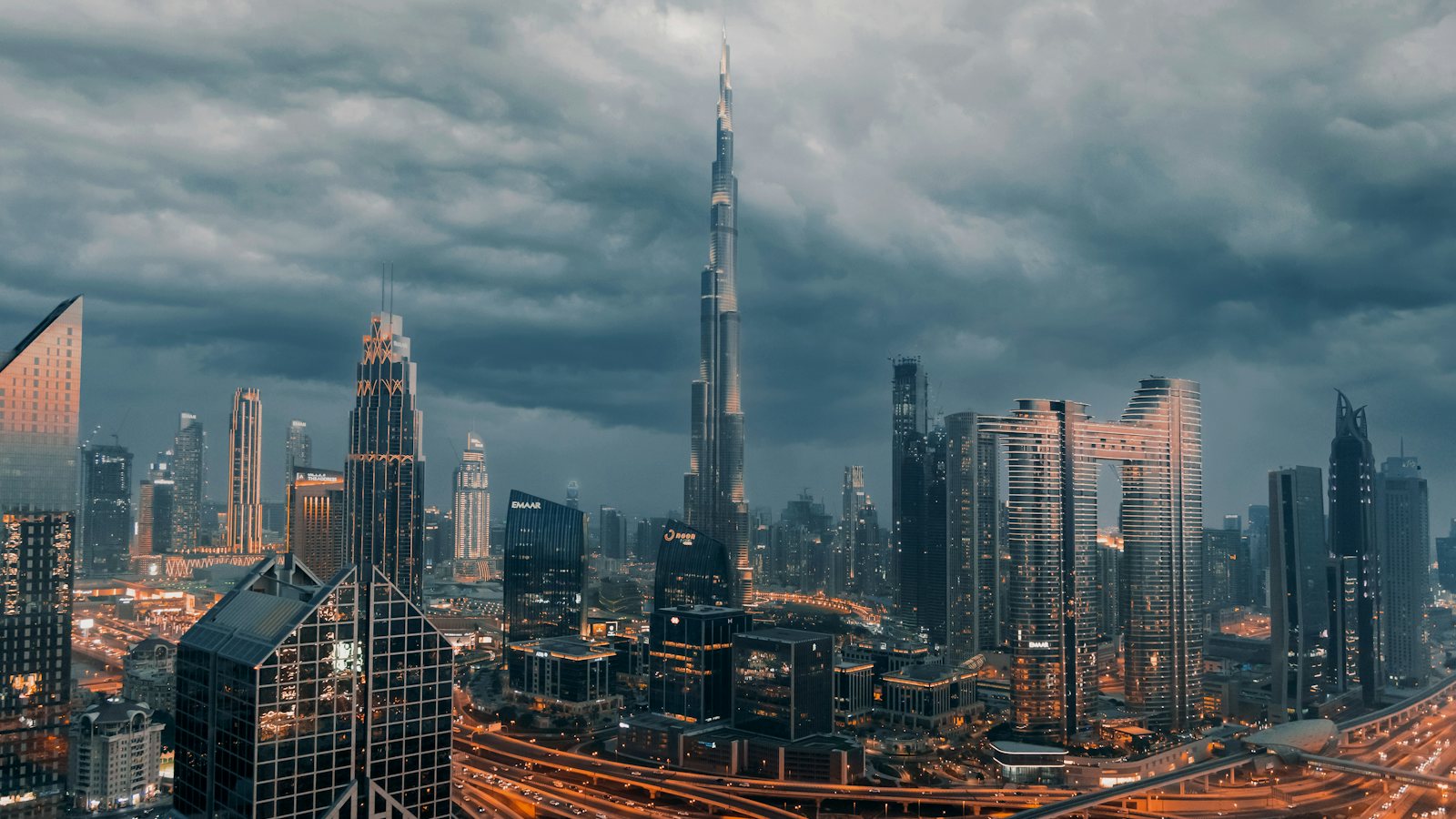The Burj Khalifa rising above the Downtown Dubai skyline under storm clouds at dusk