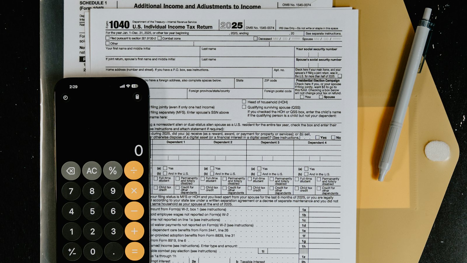 Tax forms with a calculator and pen laid out on a desk